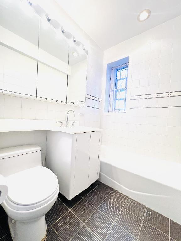 full bathroom featuring vanity, tile patterned flooring, toilet, and tiled shower / bath