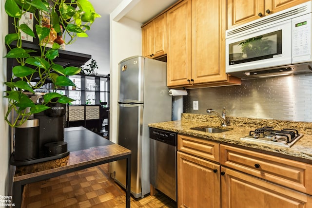 kitchen with a sink, appliances with stainless steel finishes, backsplash, and light stone countertops