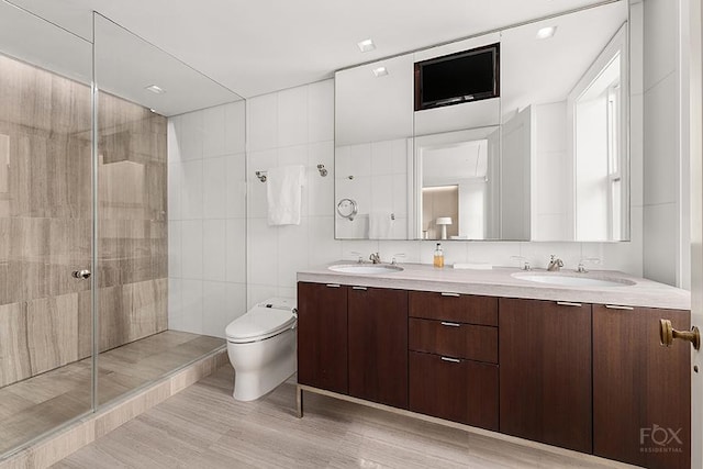 full bath featuring toilet, a shower stall, double vanity, and a sink