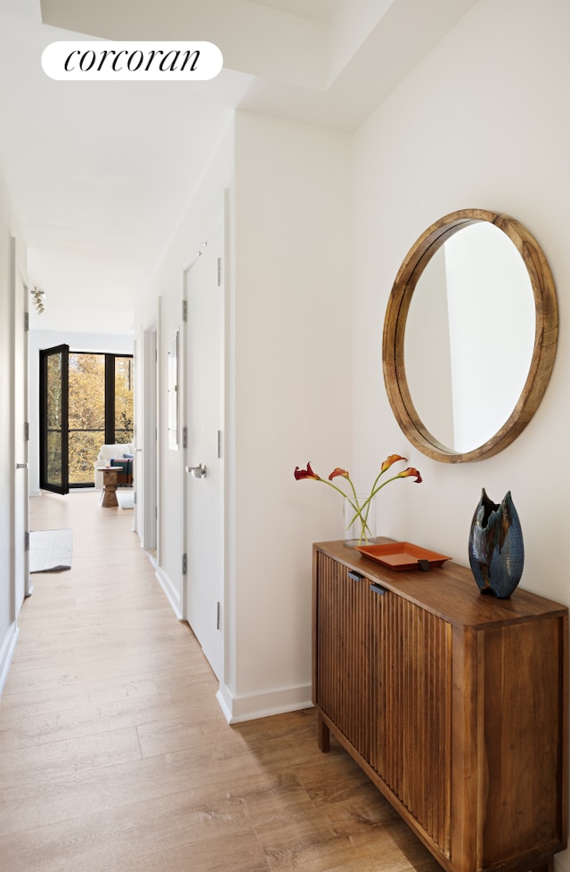 corridor featuring baseboards and light wood-type flooring