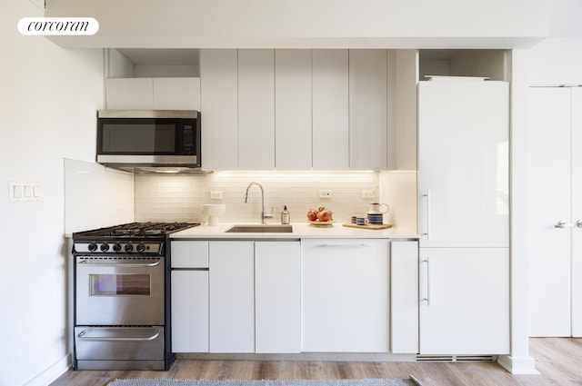 kitchen featuring light wood-style floors, stainless steel appliances, light countertops, and a sink
