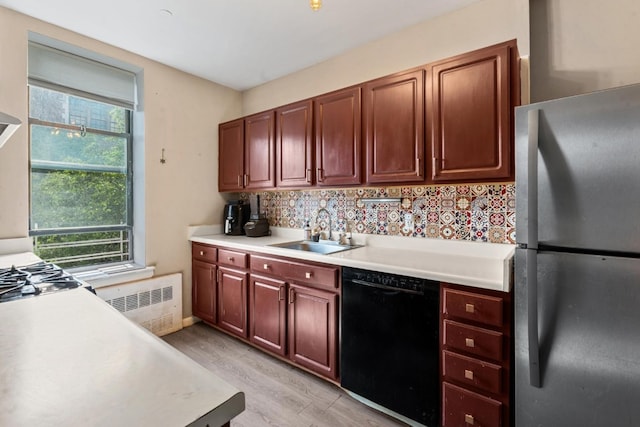 kitchen with sink, light hardwood / wood-style flooring, stainless steel refrigerator, radiator heating unit, and black dishwasher