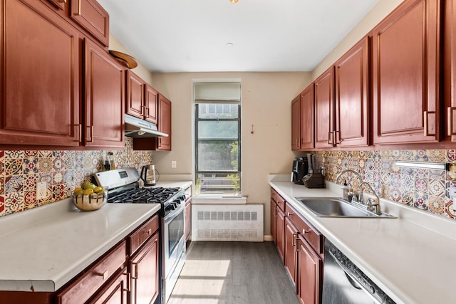 kitchen featuring radiator, appliances with stainless steel finishes, light countertops, under cabinet range hood, and a sink