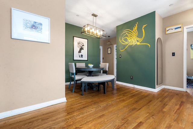 dining room featuring a notable chandelier, baseboards, and wood finished floors