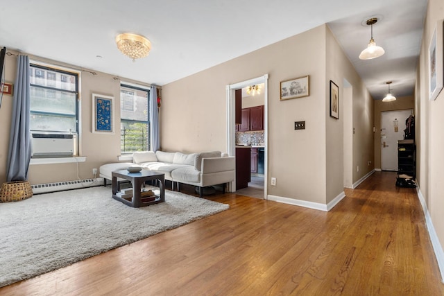 living room featuring cooling unit, baseboards, a baseboard heating unit, and wood finished floors