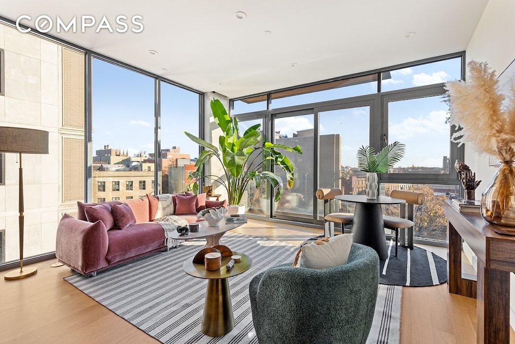 living room with a wealth of natural light, a wall of windows, and wood finished floors