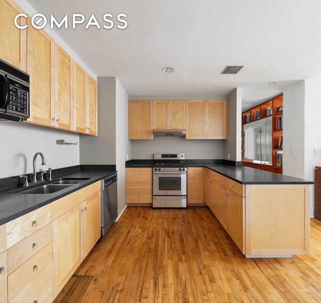 126 W 22nd St Unit 5N, New York City, NY 10011 - kitchen featuring stainless steel appliances, light brown cabinetry, a sink, a peninsula, and light wood-style floors