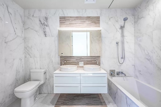 full bathroom with double vanity, toilet, a combined bath / shower with marble appearance, and a sink