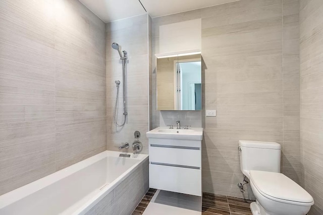full bath with tile walls, toilet, tiled shower / bath, and vanity