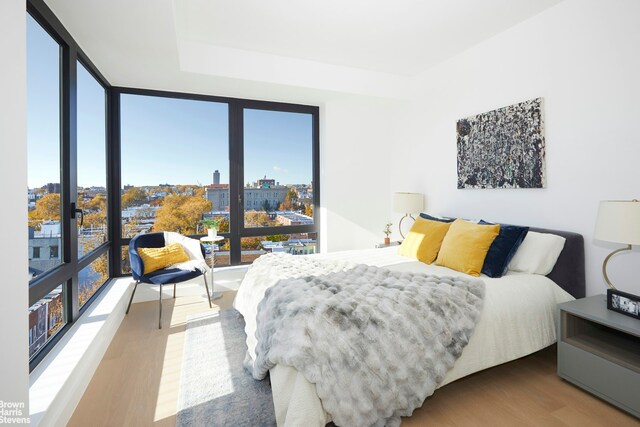 bedroom with a view of city and wood finished floors