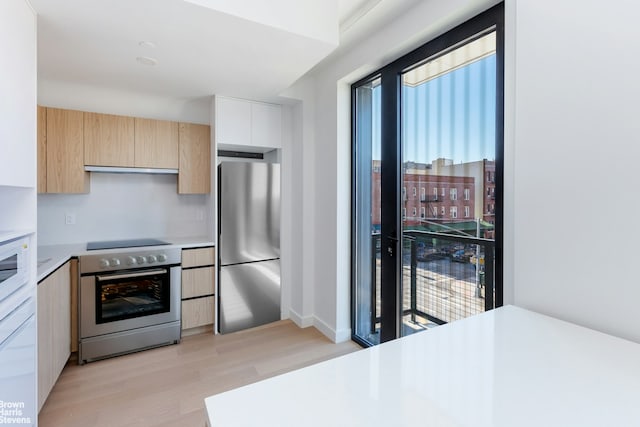 kitchen with extractor fan, light brown cabinets, light wood-style flooring, white appliances, and light countertops