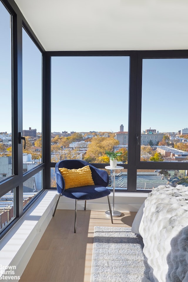 sunroom / solarium with a view of city, plenty of natural light, and wood finished floors