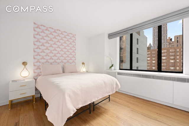 30 W 61st St Unit 9C, New York City, NY 10023 - bedroom featuring a view of city, wood finished floors, and radiator heating unit