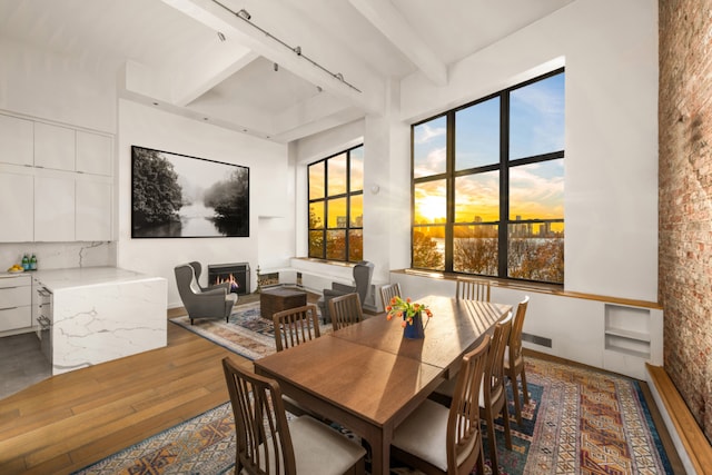 dining space with beamed ceiling and hardwood / wood-style floors