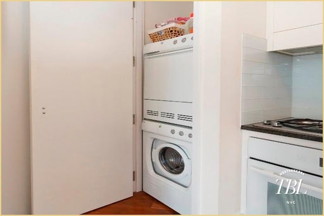 laundry room with stacked washer / drying machine and dark hardwood / wood-style flooring