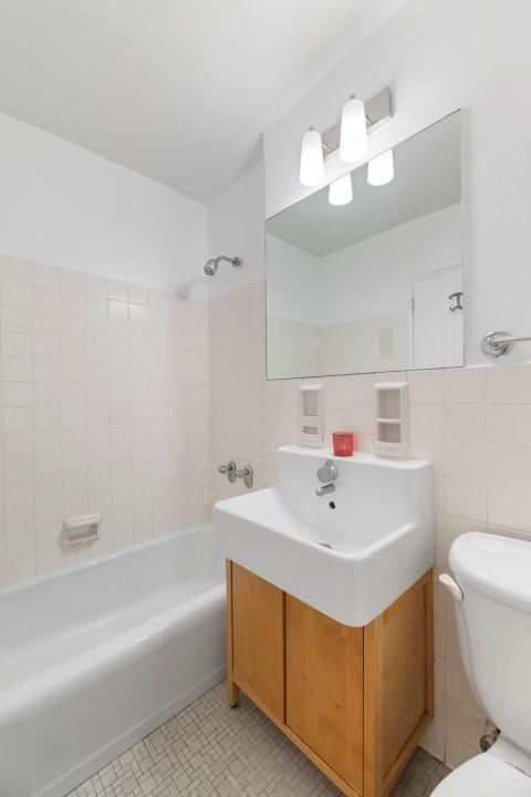 full bathroom with toilet, vanity, tile walls, and tiled shower / bath combo