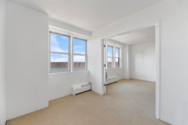 carpeted spare room featuring a baseboard heating unit