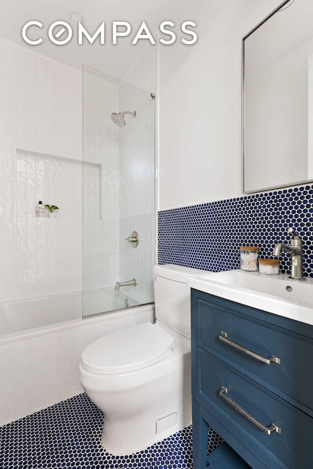 full bathroom featuring tile patterned floors, toilet, backsplash, enclosed tub / shower combo, and vanity