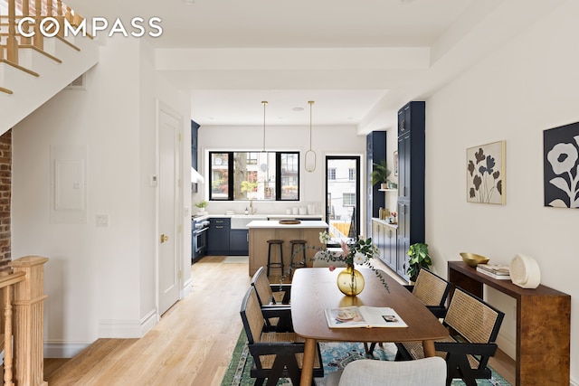 dining space featuring stairs, baseboards, light wood-style flooring, and electric panel