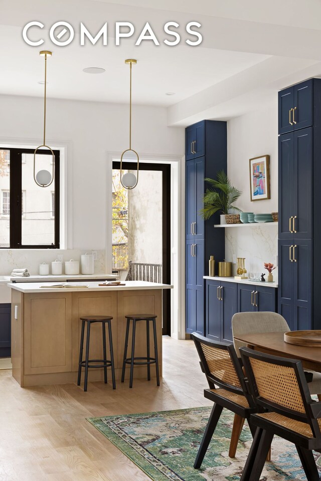 kitchen with a kitchen breakfast bar, blue cabinets, decorative light fixtures, and a kitchen island