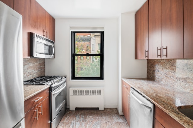 kitchen featuring radiator, sink, appliances with stainless steel finishes, light stone counters, and tasteful backsplash