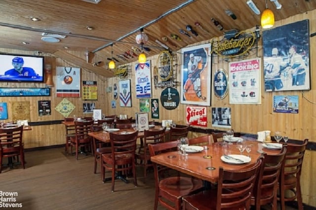 dining space with wooden ceiling, wood finished floors, and wooden walls