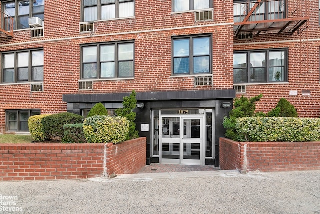 property entrance featuring cooling unit and brick siding