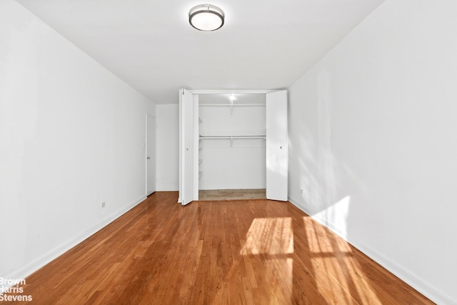 unfurnished bedroom featuring baseboards, a closet, and wood finished floors