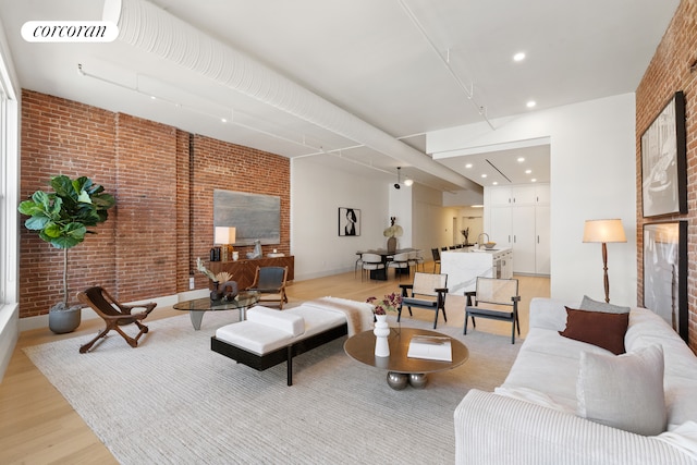 living area featuring brick wall, light wood finished floors, and visible vents