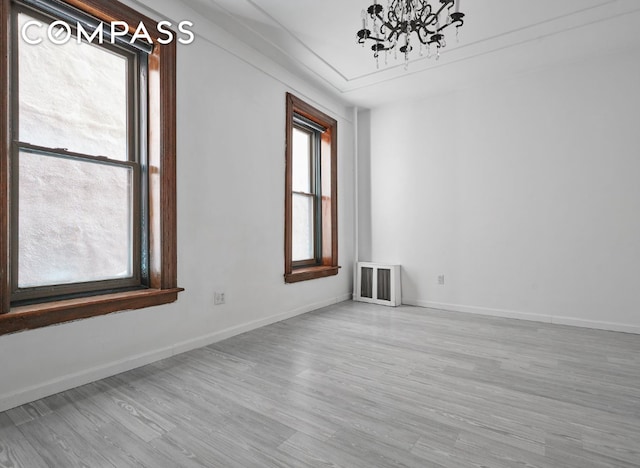 unfurnished room featuring ornamental molding, a notable chandelier, and light wood-type flooring