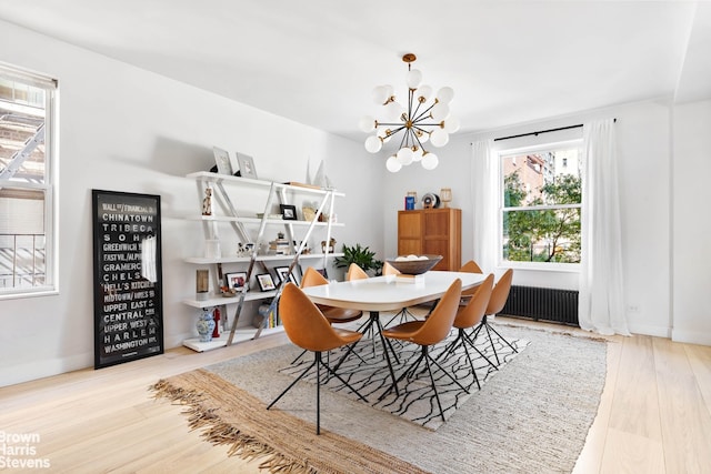 dining room with light wood-style floors, radiator, a notable chandelier, and baseboards