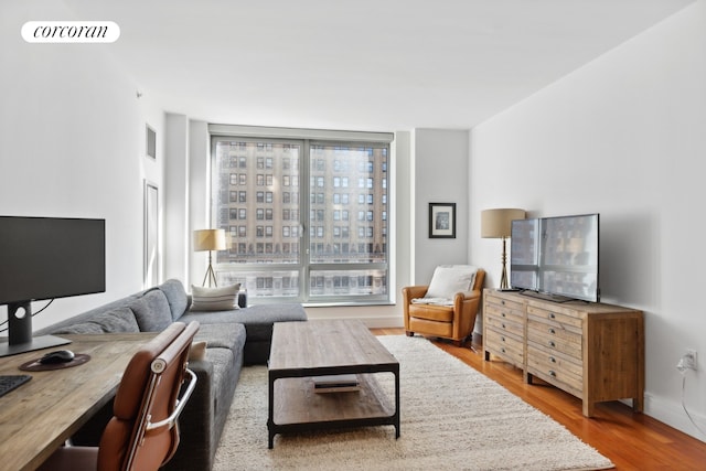 living area featuring baseboards, visible vents, and wood finished floors