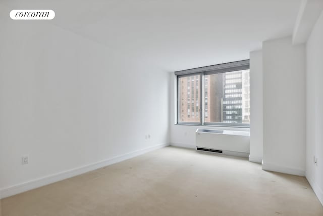 spare room with baseboards and light carpet