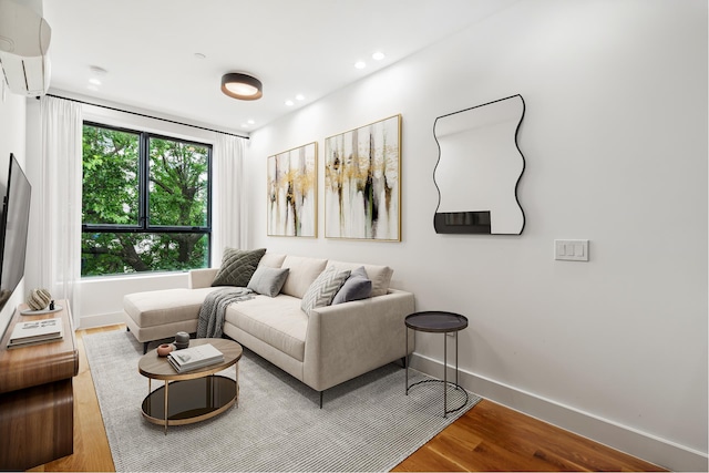 living area featuring recessed lighting, a wall mounted air conditioner, wood finished floors, and baseboards