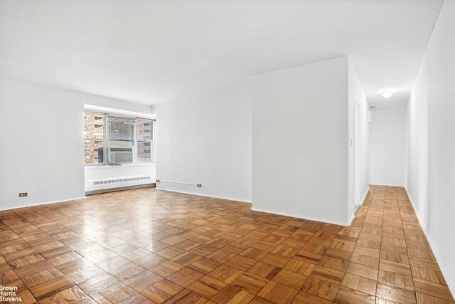 unfurnished room featuring radiator heating unit and light parquet floors