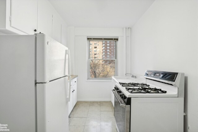 kitchen with ceiling fan, white appliances, white cabinets, and light tile patterned flooring