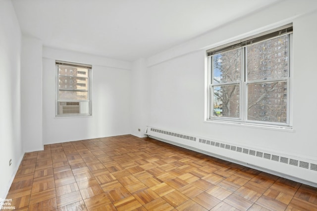 spare room with cooling unit, a baseboard radiator, and light parquet floors