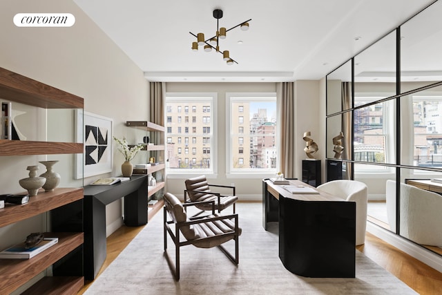 office space featuring a city view, visible vents, baseboards, light wood finished floors, and an inviting chandelier