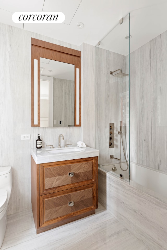 bathroom with toilet, a marble finish shower, vanity, and tile walls