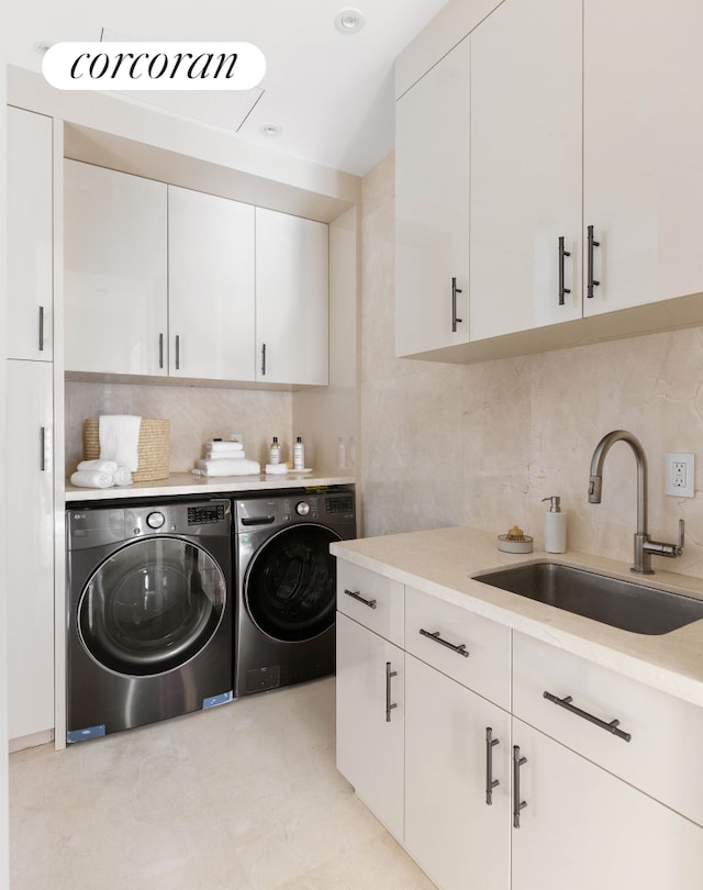 laundry room with cabinet space, independent washer and dryer, and a sink