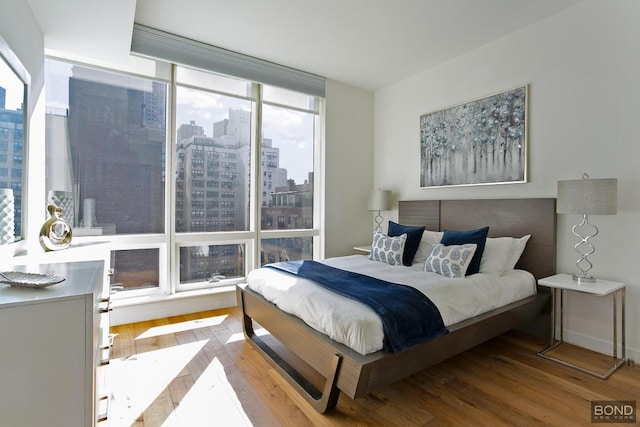 bedroom with expansive windows and wood-type flooring