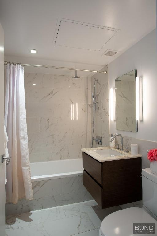 full bathroom featuring shower / tub combo with curtain, vanity, and toilet