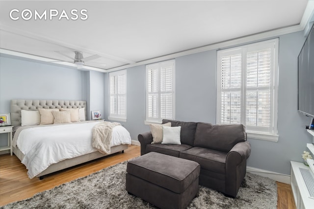 bedroom with multiple windows, ornamental molding, baseboards, and wood finished floors