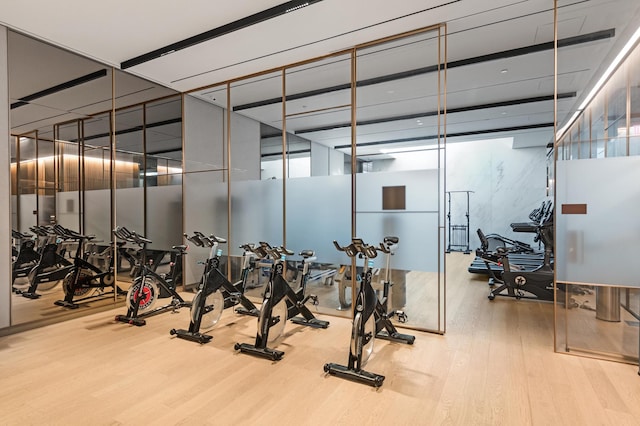 workout area with a wall of windows and wood finished floors