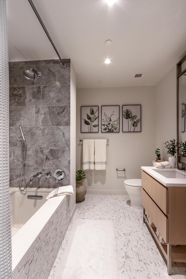 bathroom featuring vanity, baseboards, visible vents, toilet, and tiled shower / bath