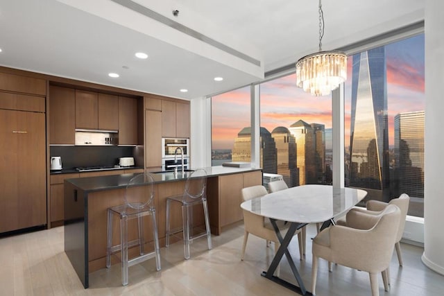 kitchen featuring sink, decorative light fixtures, a chandelier, gas cooktop, and an island with sink