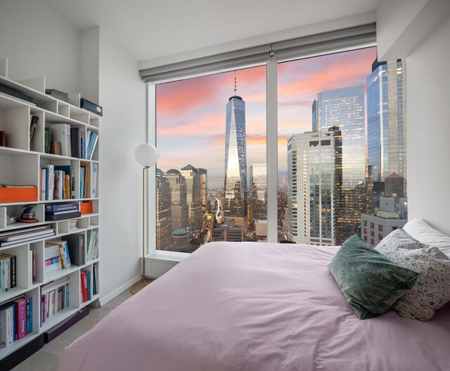 bedroom with a view of city, baseboards, and a wall of windows