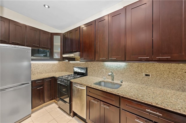 kitchen with stainless steel appliances, tasteful backsplash, sink, light stone counters, and light tile patterned floors