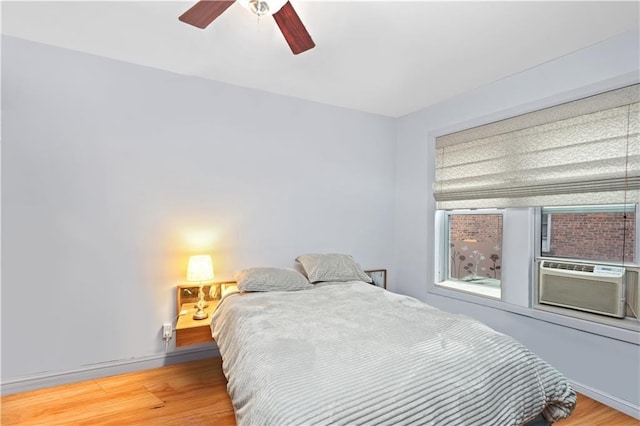 bedroom with ceiling fan, cooling unit, and wood-type flooring