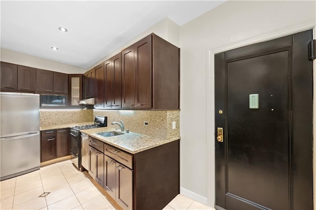 kitchen with light tile patterned floors, gas range, stainless steel refrigerator, light stone counters, and sink